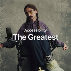 An image of a power chair user using their iPhone. The text 'Accessibility, The Greatest' sits over the photo.
