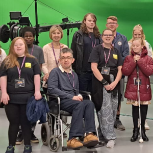 Disabled trainees smile for the camera in front of a green screen at BBC Wales.