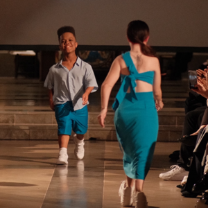 Two models of short stature walk down a catwalk in a DEWEY fashion show.