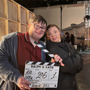The two stars of Ralph and Katie, Leon Harrop and Sarah Gordy, pose with a clapperboard,